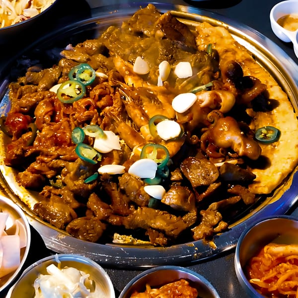 A large Korean BBQ platter with marinated meats, shrimp, octopus, garlic, and jalapeños.